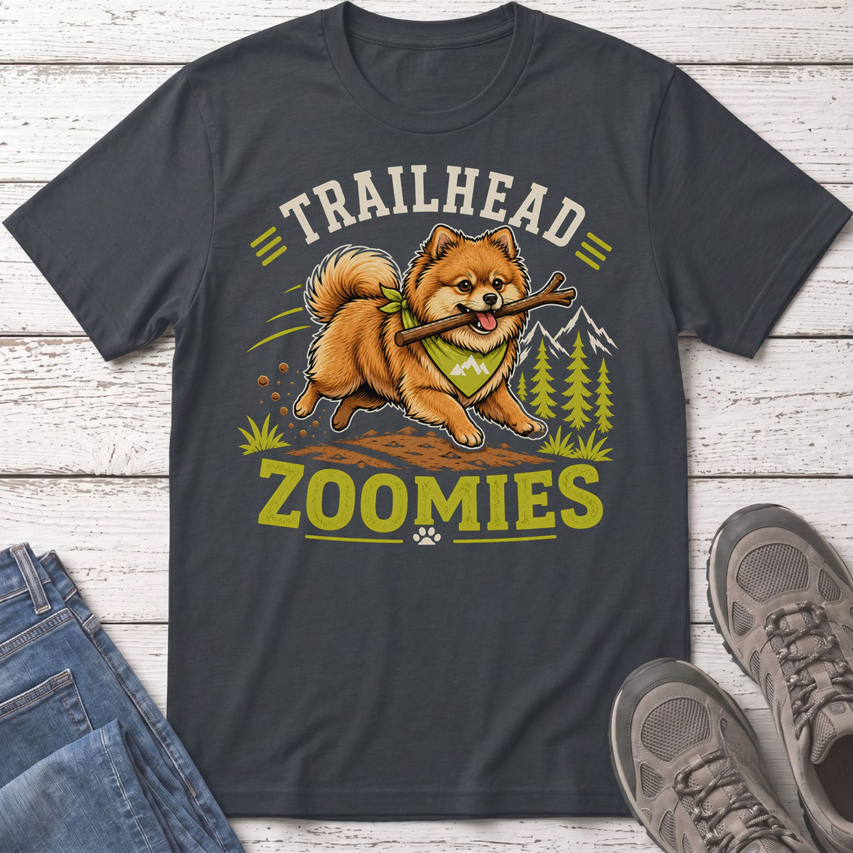 Pomeranian dog with stick runs through forest with text "TRAILHEAD ZOOMIES".