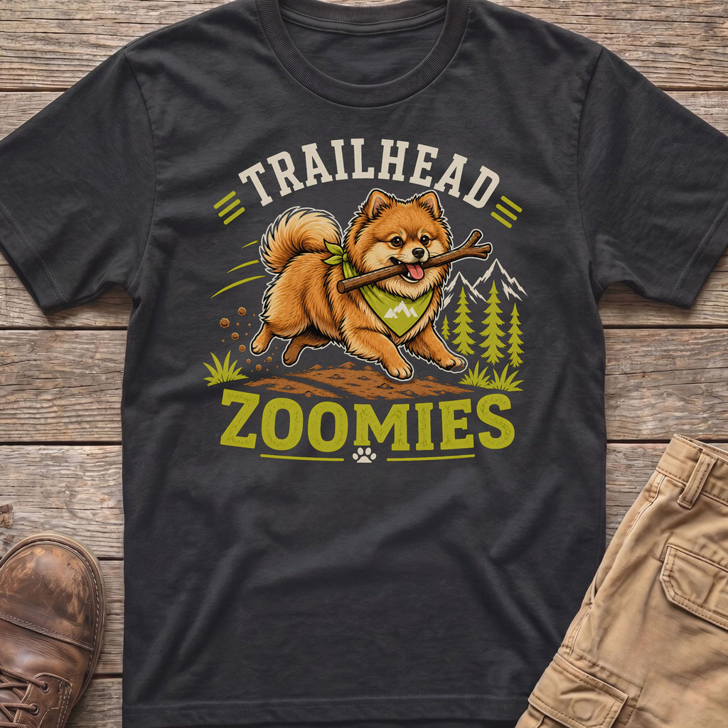 Pomeranian dog with stick on shirt saying "TRAILHEAD ZOOMIES"