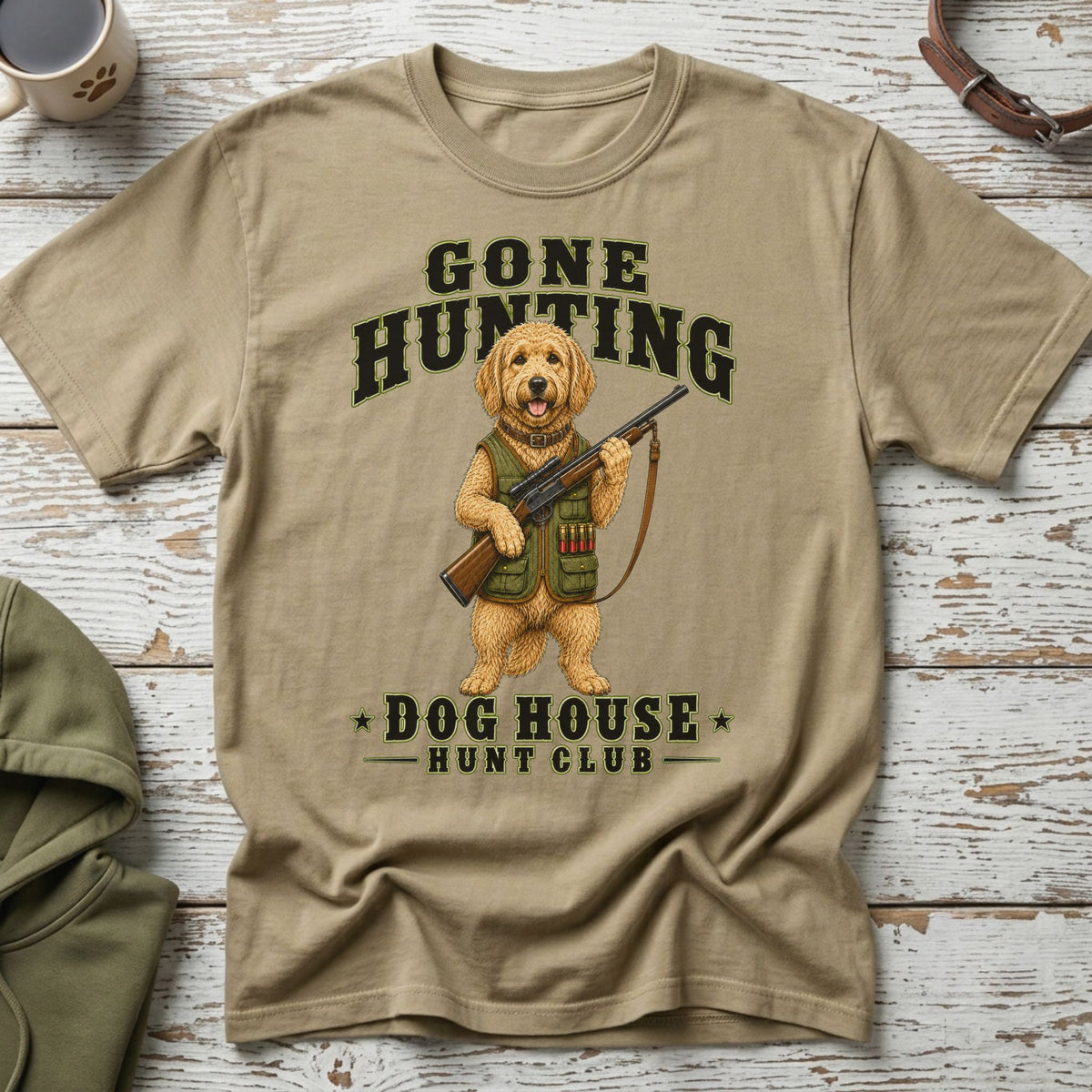 Tan t-shirt with a dog holding a shotgun and text "Gone Hunting Dog House Hunt Club".