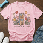 Pink t-shirt with a cartoon Yorkshire Terrier sitting among colorful tulips with the text "Paws in Bloom".