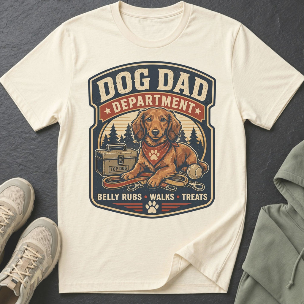 Cream t-shirt with "Dog Dad Department" graphic, featuring a dachshund, toolbox, and dog essentials.