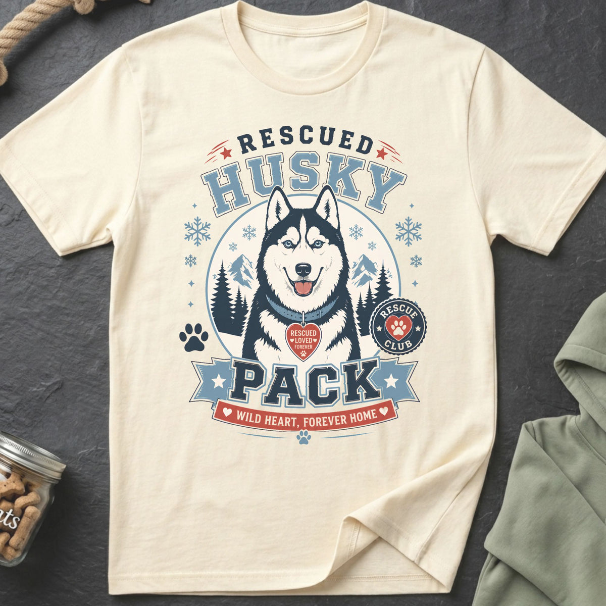 Cream t-shirt with a graphic of a rescued husky, snowflakes, and text "Rescued Husky Pack".
