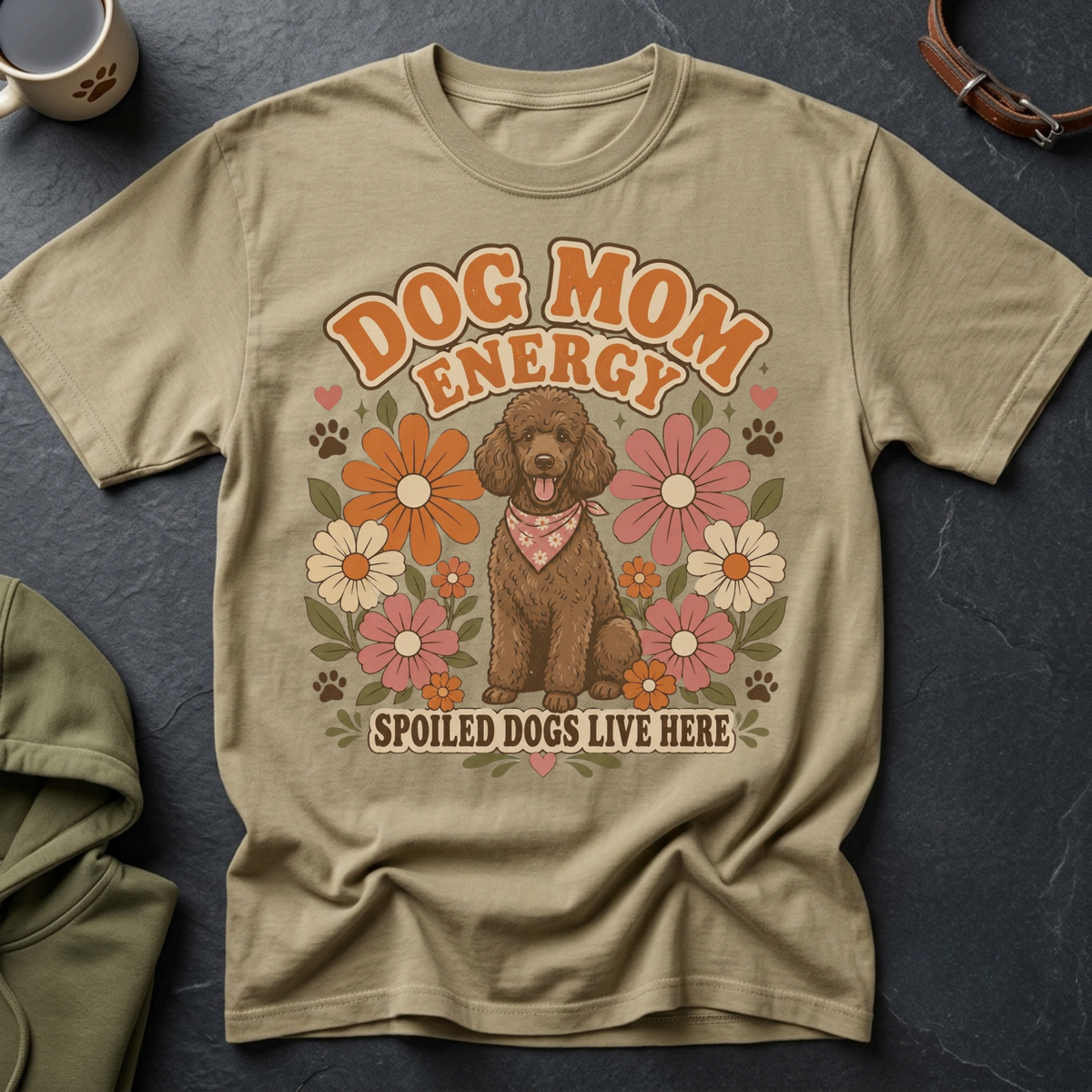 A brown poodle wearing a bandana sits among retro flowers on a tan t-shirt with text.