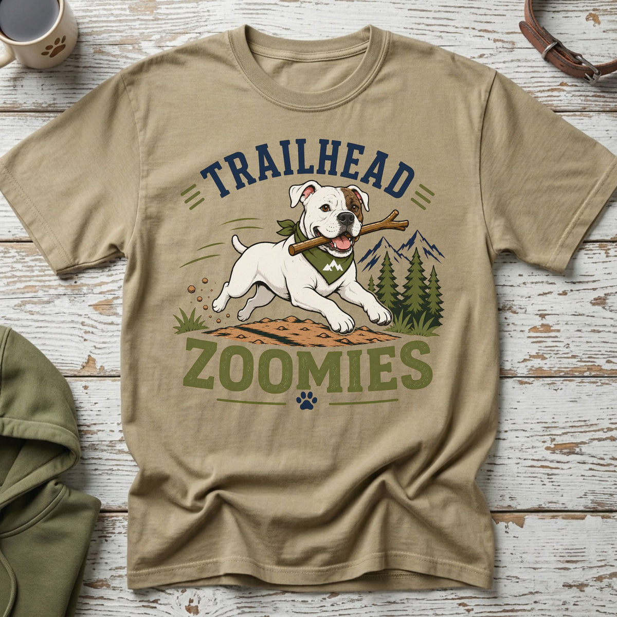 White dog with stick and bandana, text "TRAILHEAD ZOOMIES" and mountains.
