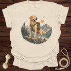 Golden retriever wearing backpack stands on rock with mountain and lake background.