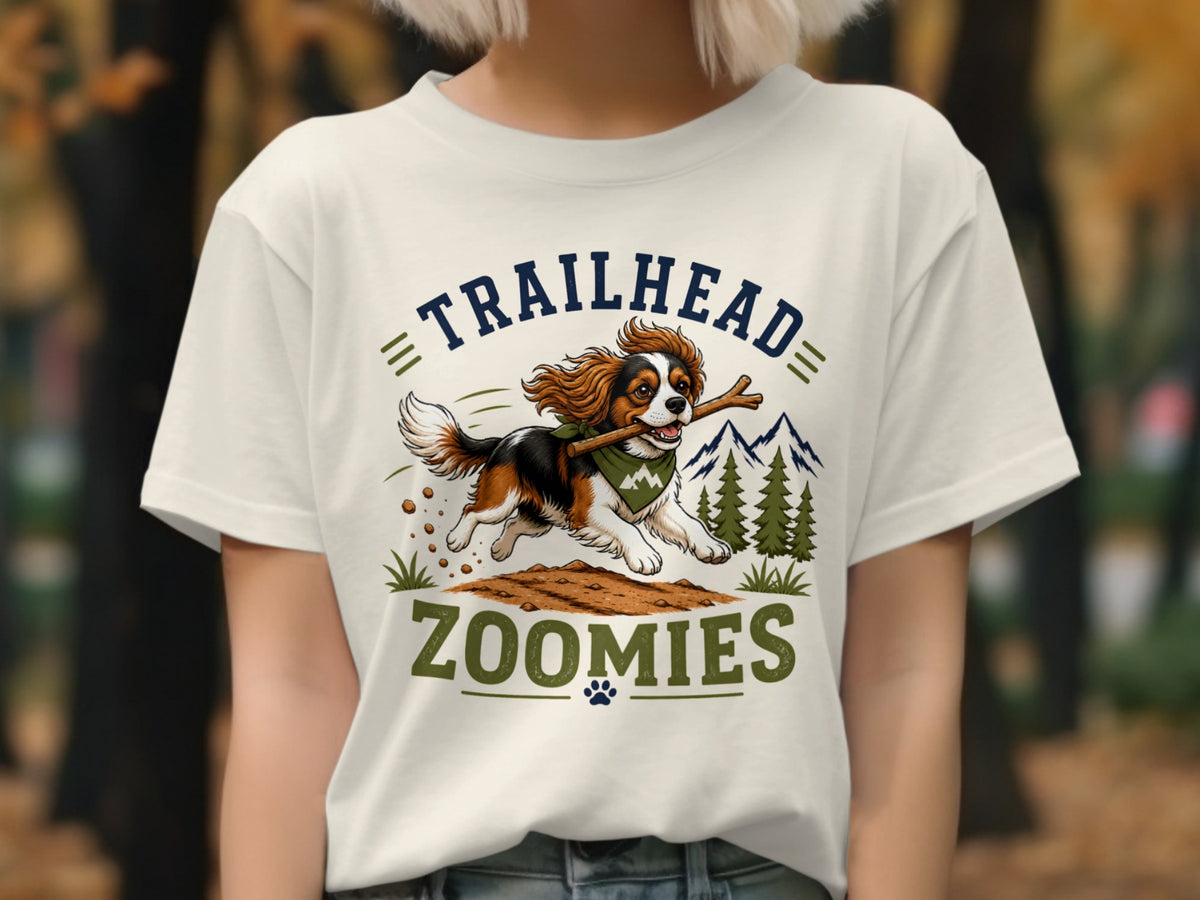 Tricolor dog with stick runs with text "TRAILHEAD ZOOMIES" on t-shirt.
