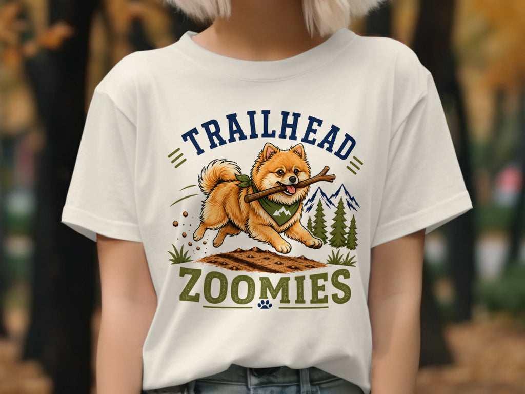 Pomeranian dog running with stick, text "TRAILHEAD ZOOMIES" and mountains.