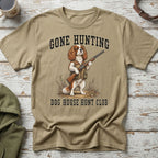 Tan t-shirt with Cavalier King Charles Spaniel wearing vest and holding rifle, text "GONE HUNTING DOG HOUSE HUNT CLUB".