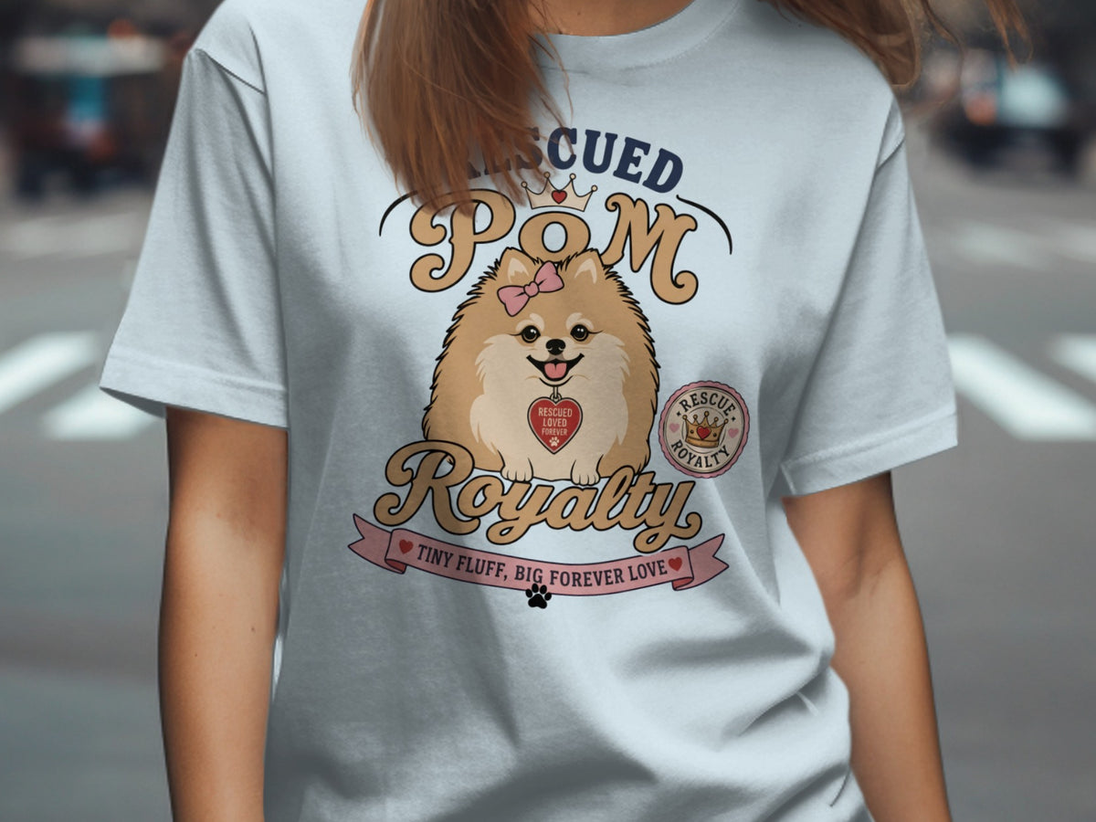 Light blue t-shirt with a Pomeranian wearing a bow, reading "Rescued Pom Royalty".