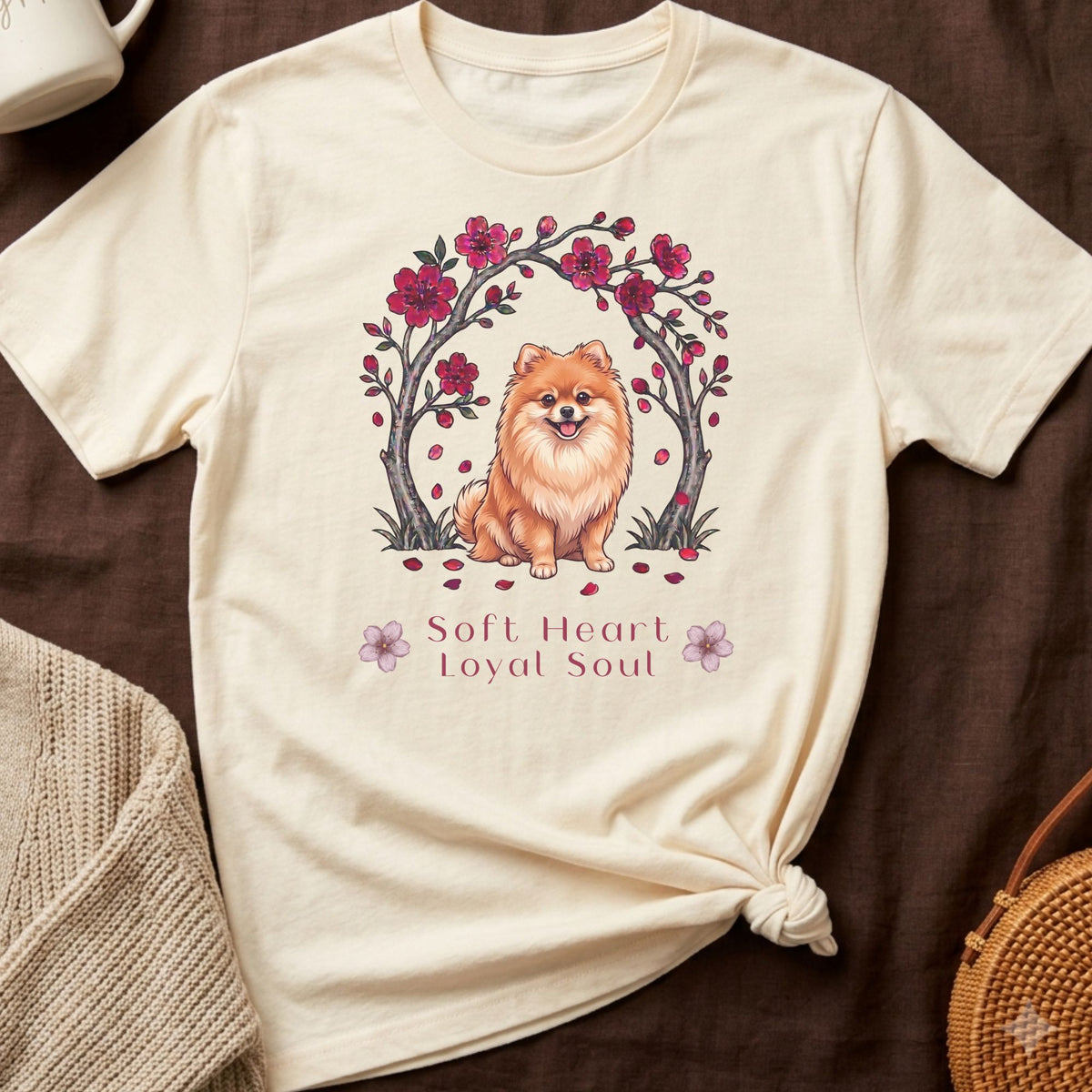 Cream t-shirt with illustrated Pomeranian dog under a floral arch.