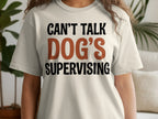 Cream t-shirt with "CAN'T TALK DOG'S SUPERVISING" text.
