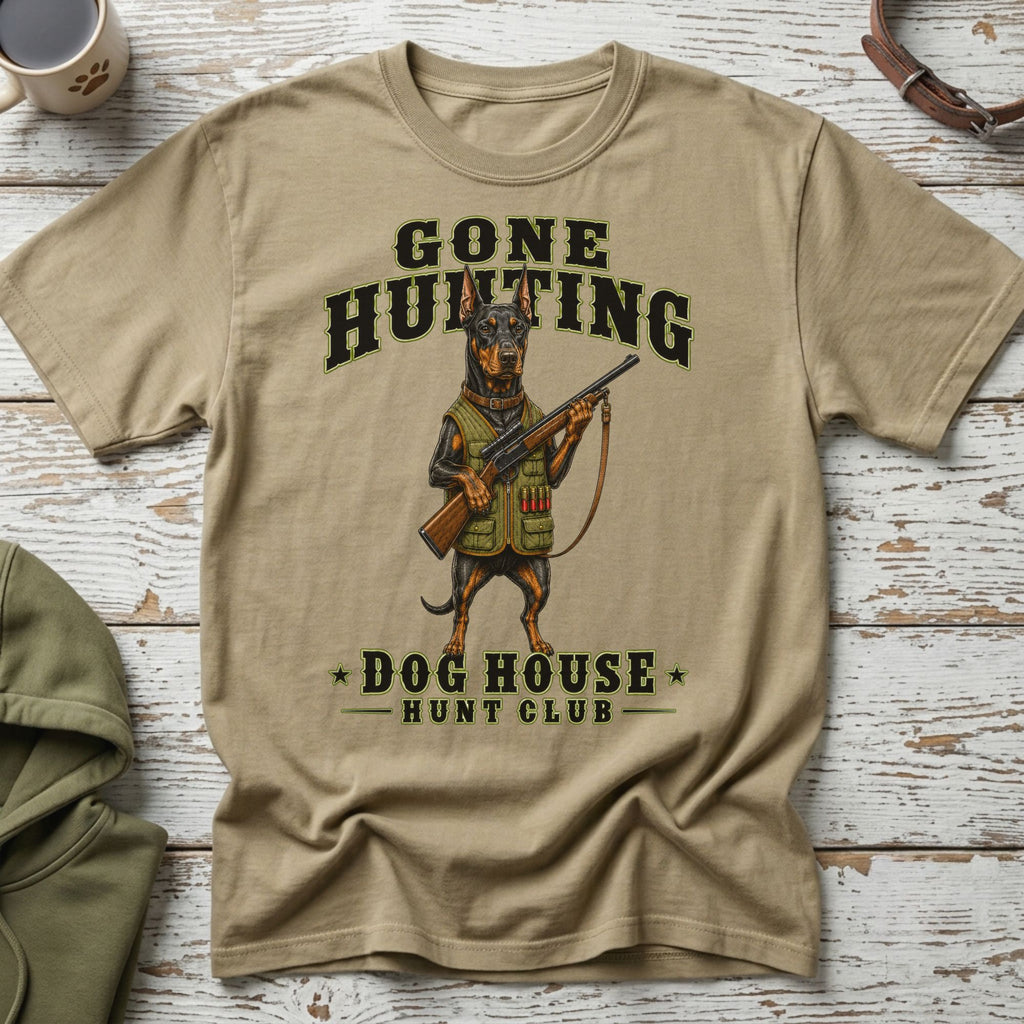 T-shirt with a Doberman holding a shotgun, text "GONE HUNTING DOG HOUSE HUNT CLUB".