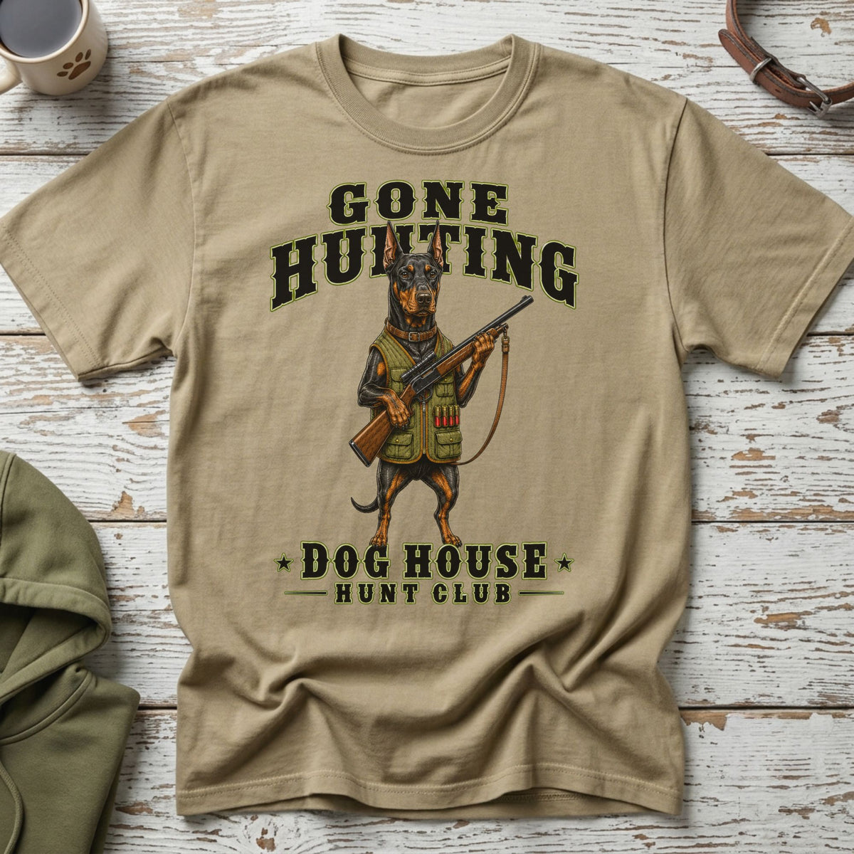T-shirt with a Doberman holding a shotgun, text "GONE HUNTING DOG HOUSE HUNT CLUB".