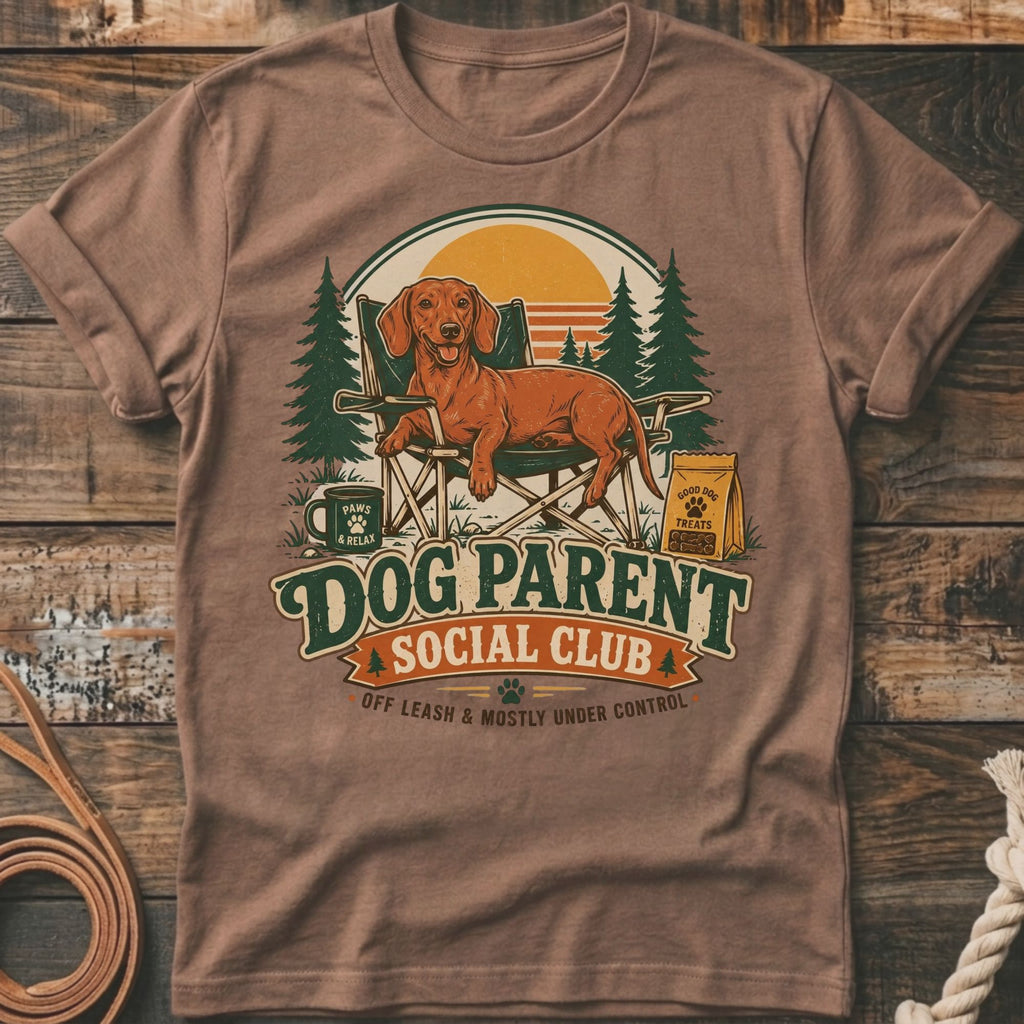 Brown t-shirt with dachshund on chair, "Dog Parent Social Club" text, and dog treats bag.