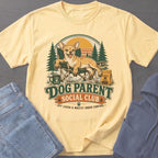 Yellow t-shirt graphic with a chihuahua, camp chairs, trees, and text "Dog Parent Social Club".