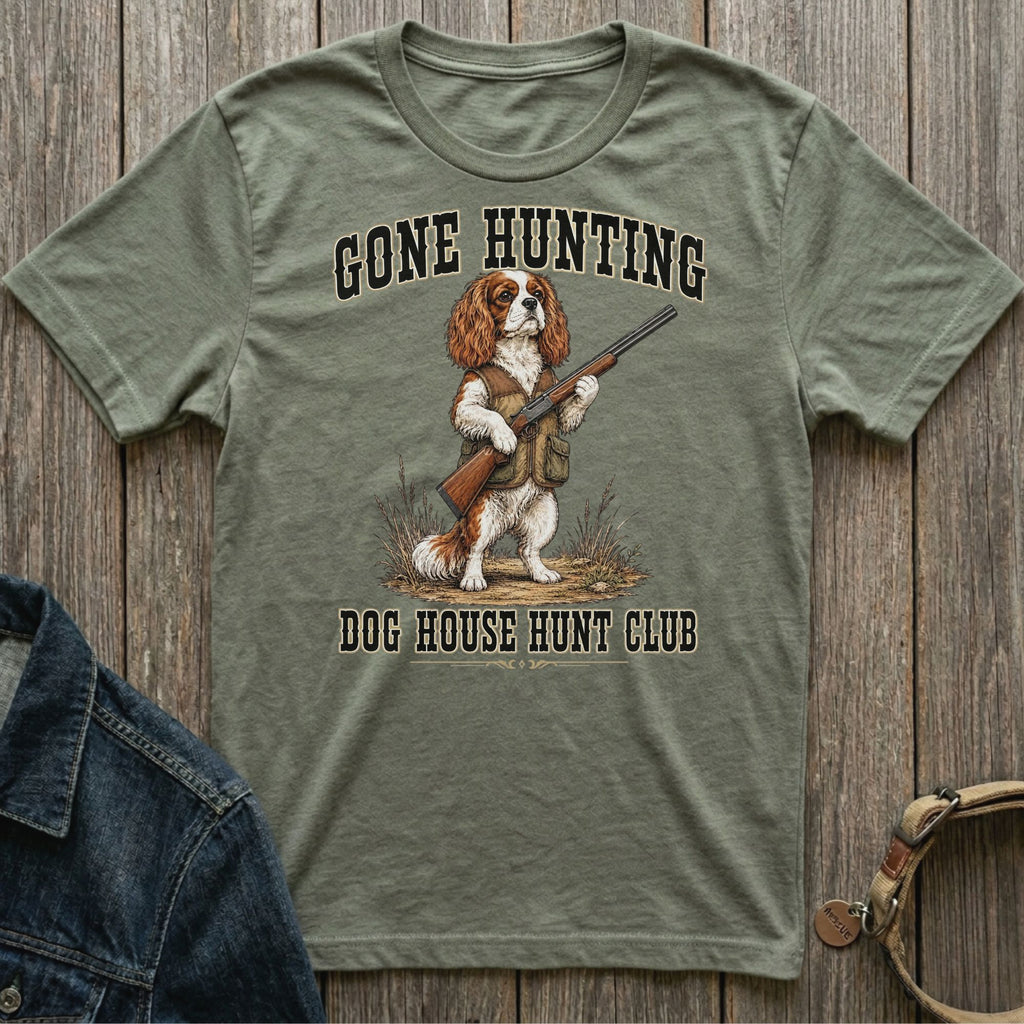 Dog wearing hunting vest and holding shotgun, text "GONE HUNTING DOG HOUSE HUNT CLUB".