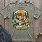 Dog Parent Social Club t-shirt with a dog relaxing outdoors with text.