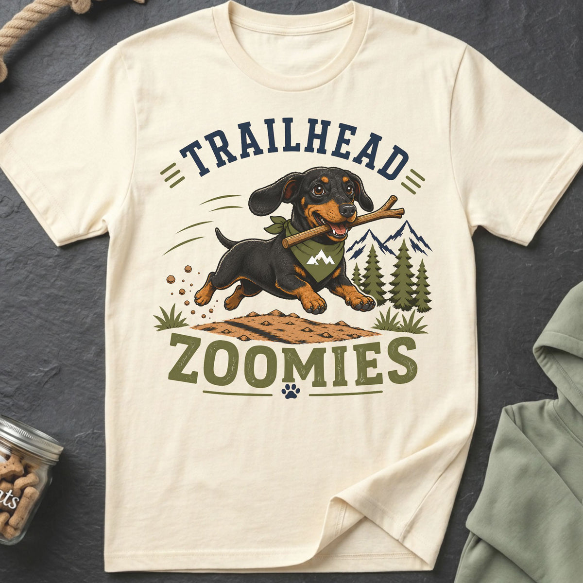 Dachshund with stick running through nature, with text "TRAILHEAD ZOOMIES".