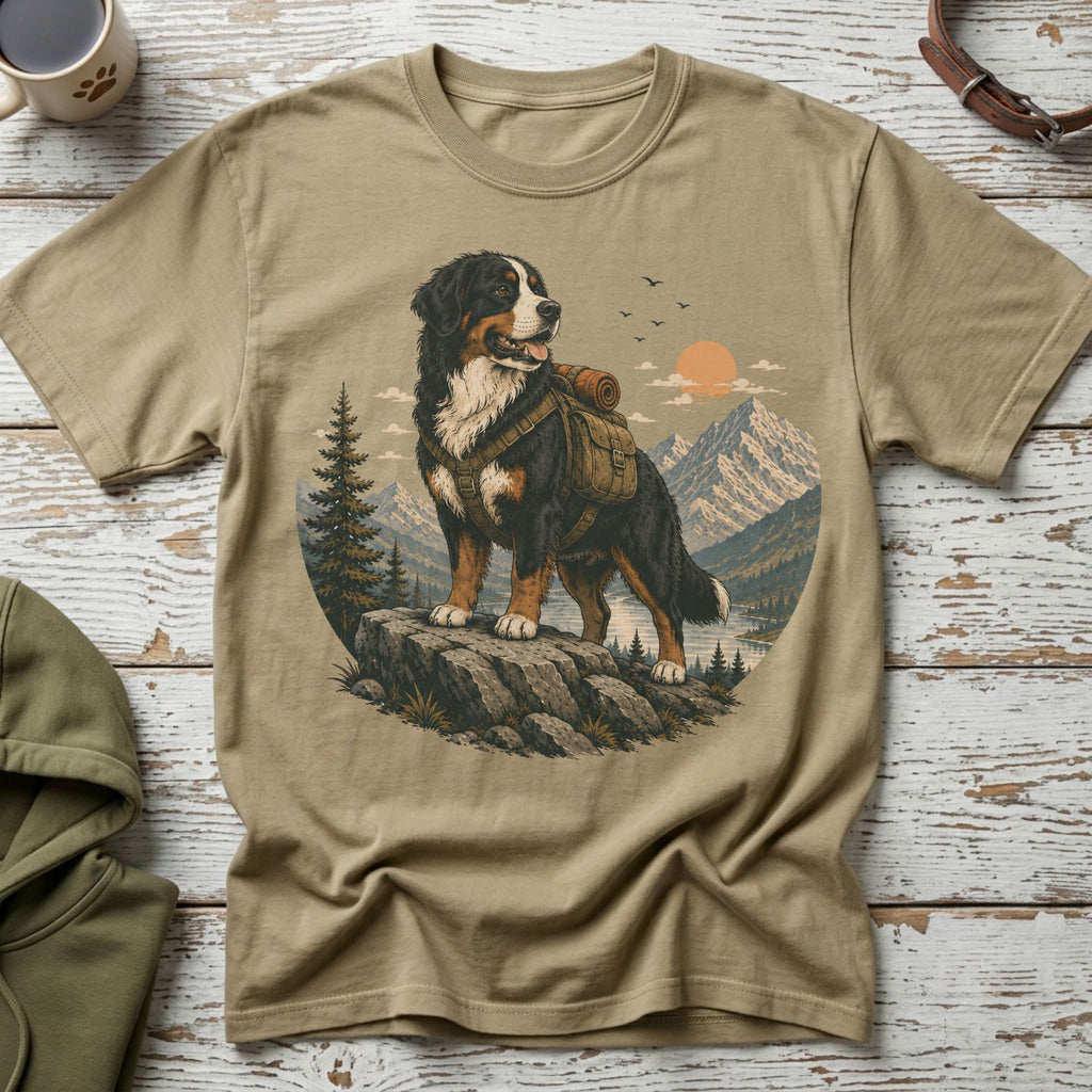 Bernese Mountain Dog wearing a backpack on a rocky ledge overlooking mountains and a lake.