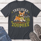 Corgi with stick running through trees, text reads "TRAILHEAD ZOOMIES".