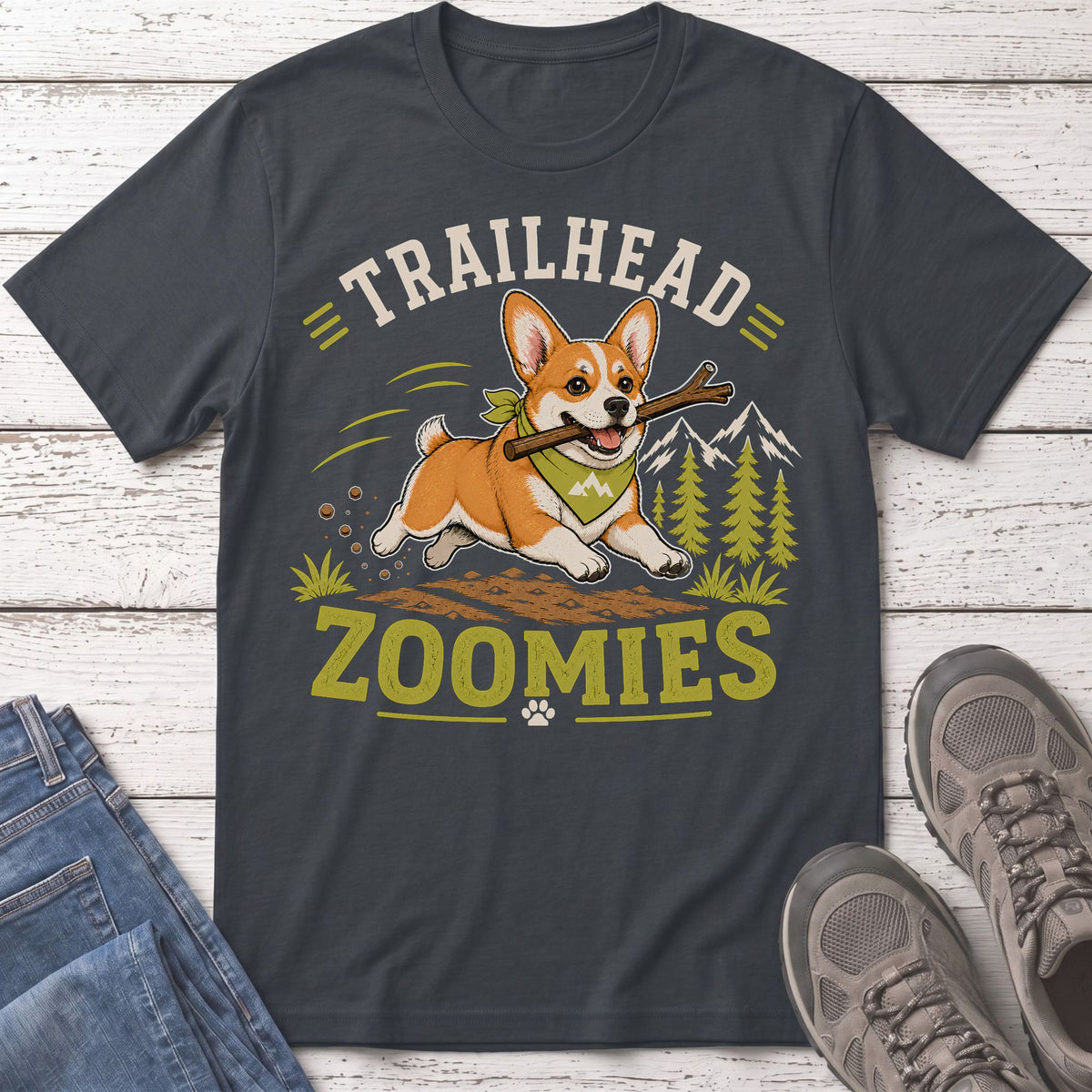 Corgi with stick running through trees, text reads "TRAILHEAD ZOOMIES".