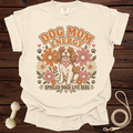 Cream t-shirt with "DOG MOM ENERGY" and a dog surrounded by retro flowers.